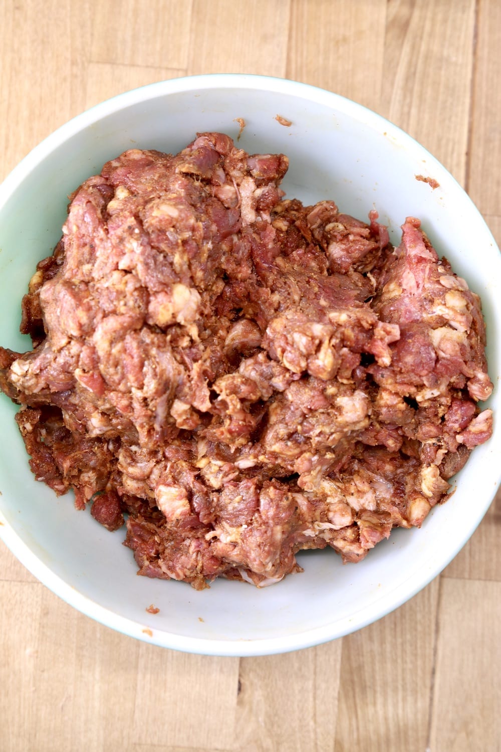 coarse ground beef - chili meat mixed with spices in a bowl -overhead