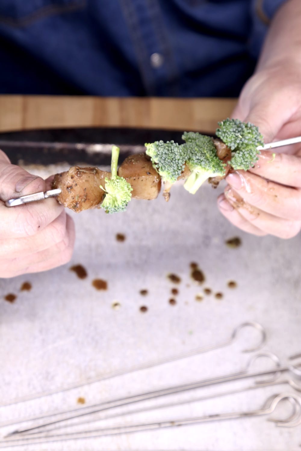 threading broccoli and chicken onto skewers