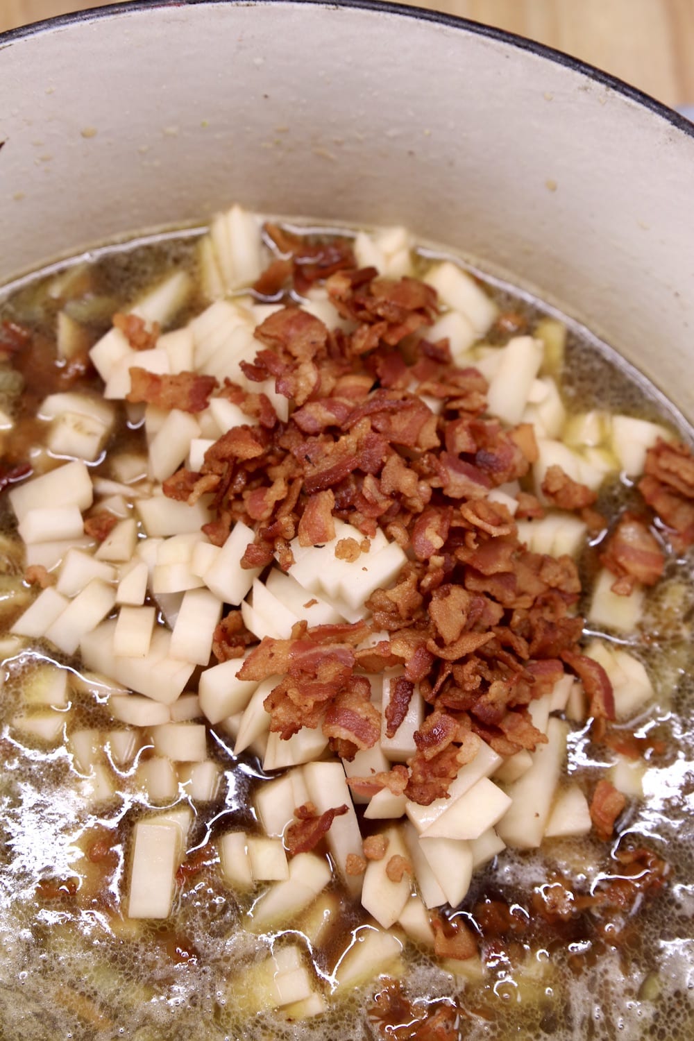 adding diced potatoes and cooked bacon to soup