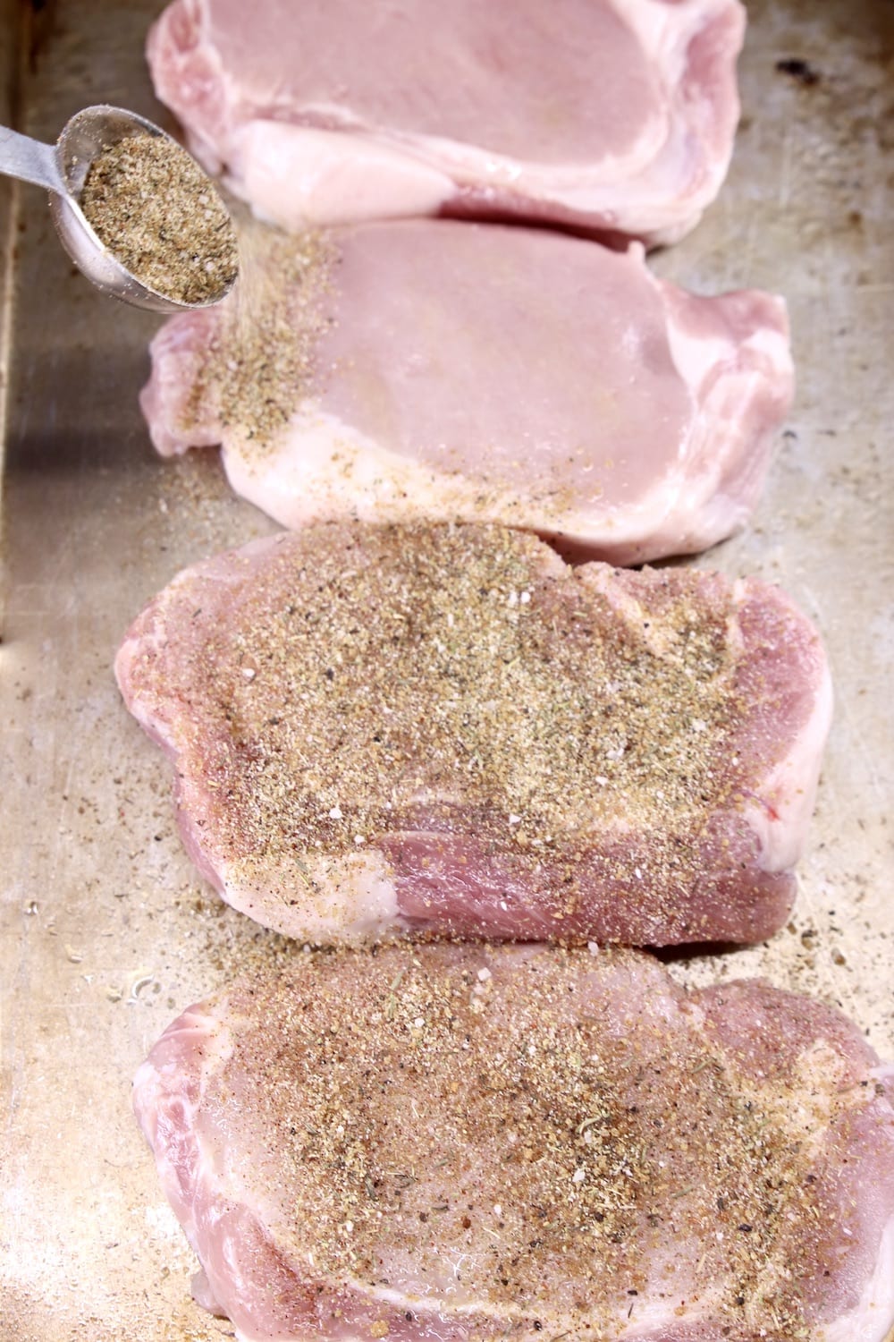 sprinkling dry rub on pork chops