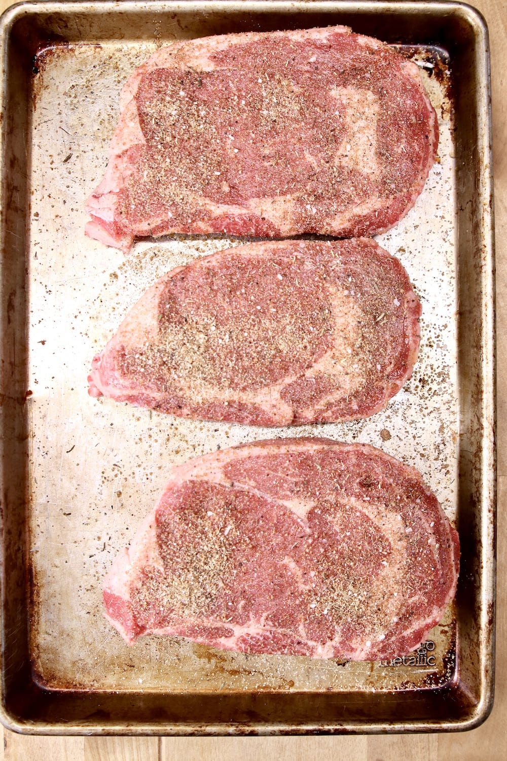 Dry rubbed ribeye steaks on a sheet pan