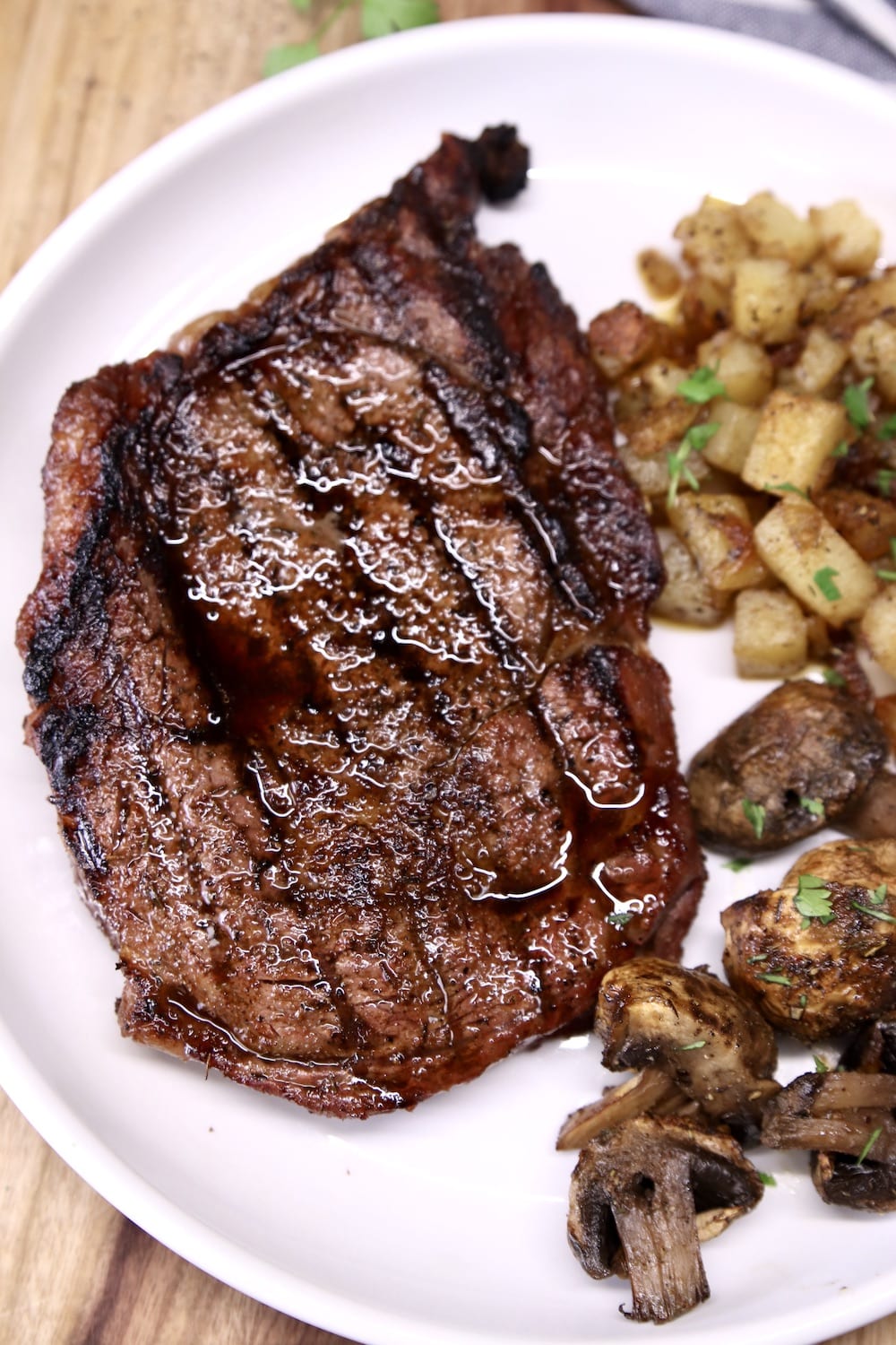 Grilled ribeye steak with potatoes and mushrooms on a plate