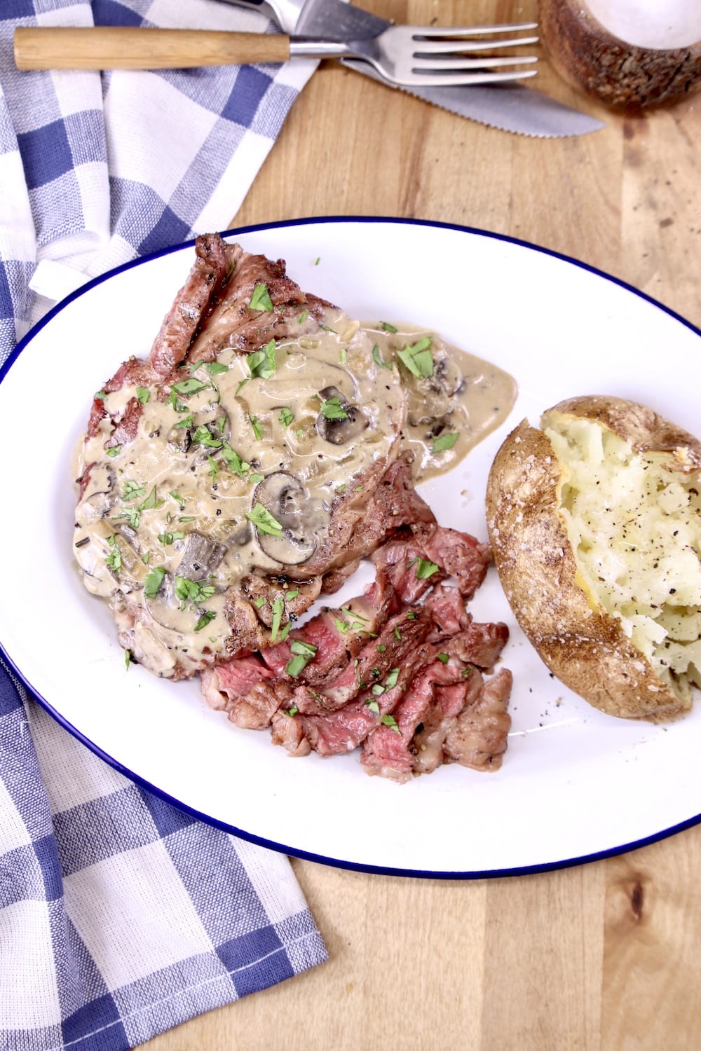 Grilled steak with mushroom cream sauce served with baked potato