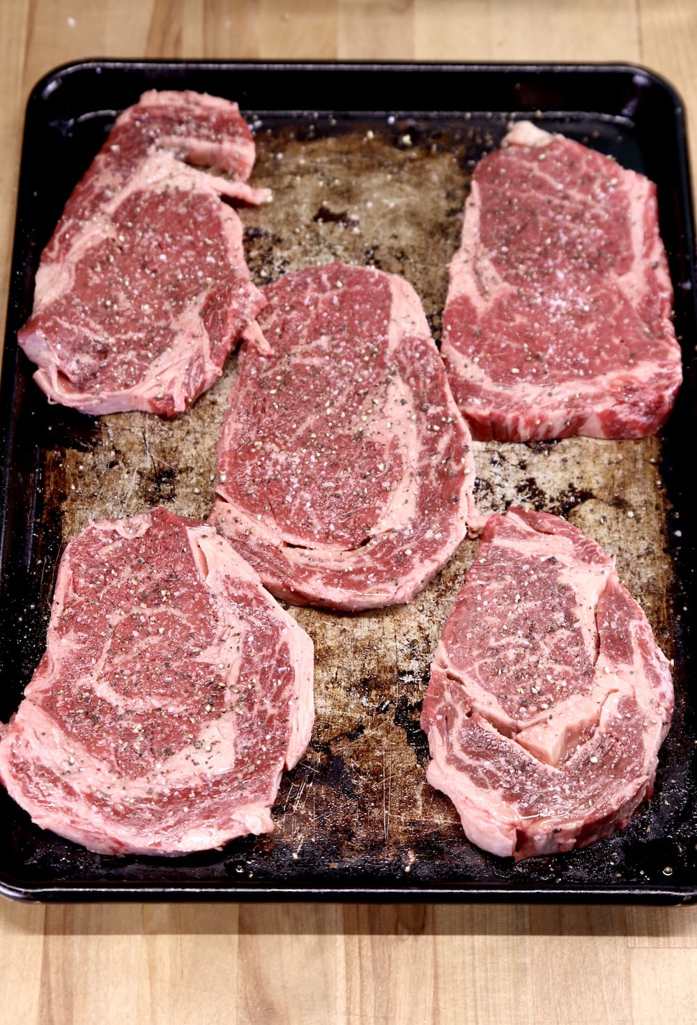 ribeye steaks seasoned with salt and pepper for grilling