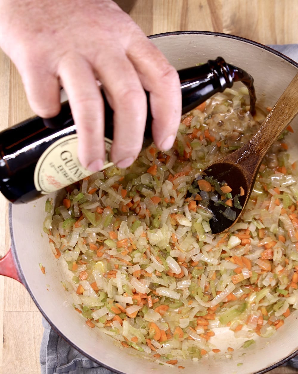 pouring a bottle of Guinness Stout to vegetables for stew