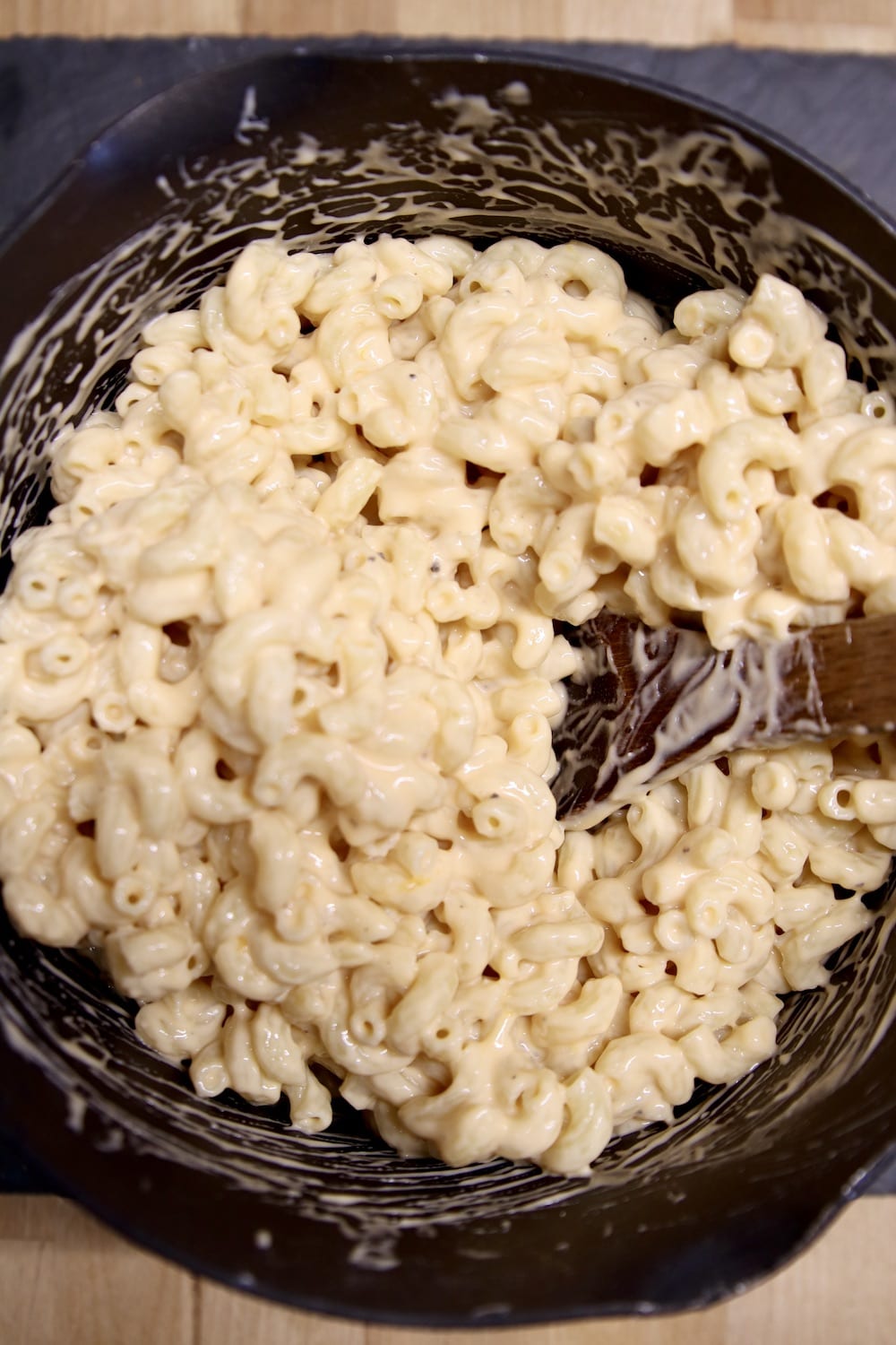 macaroni and cheese in a pan with wood spoon
