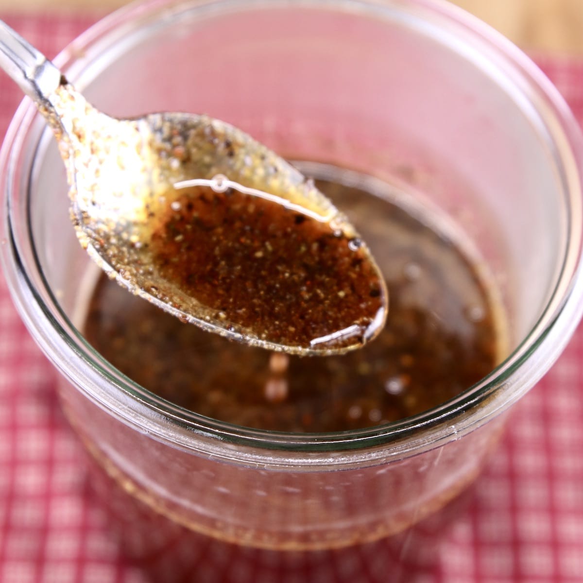 Maple Glaze in a glass jar with spoon dipping into sauce - jar on red napkin