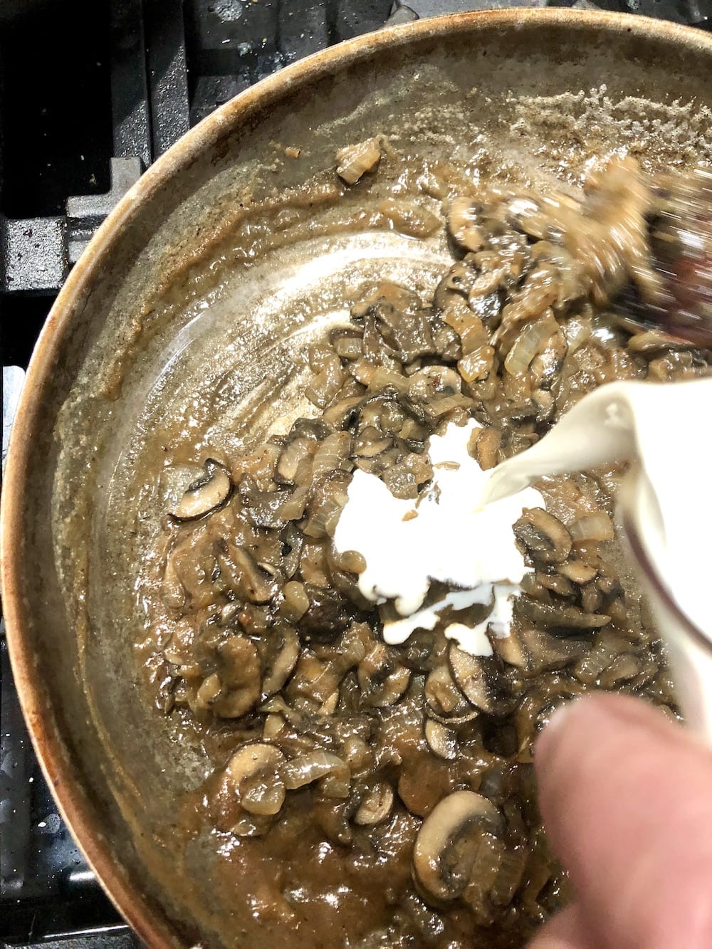 adding cream to mushroom sauce