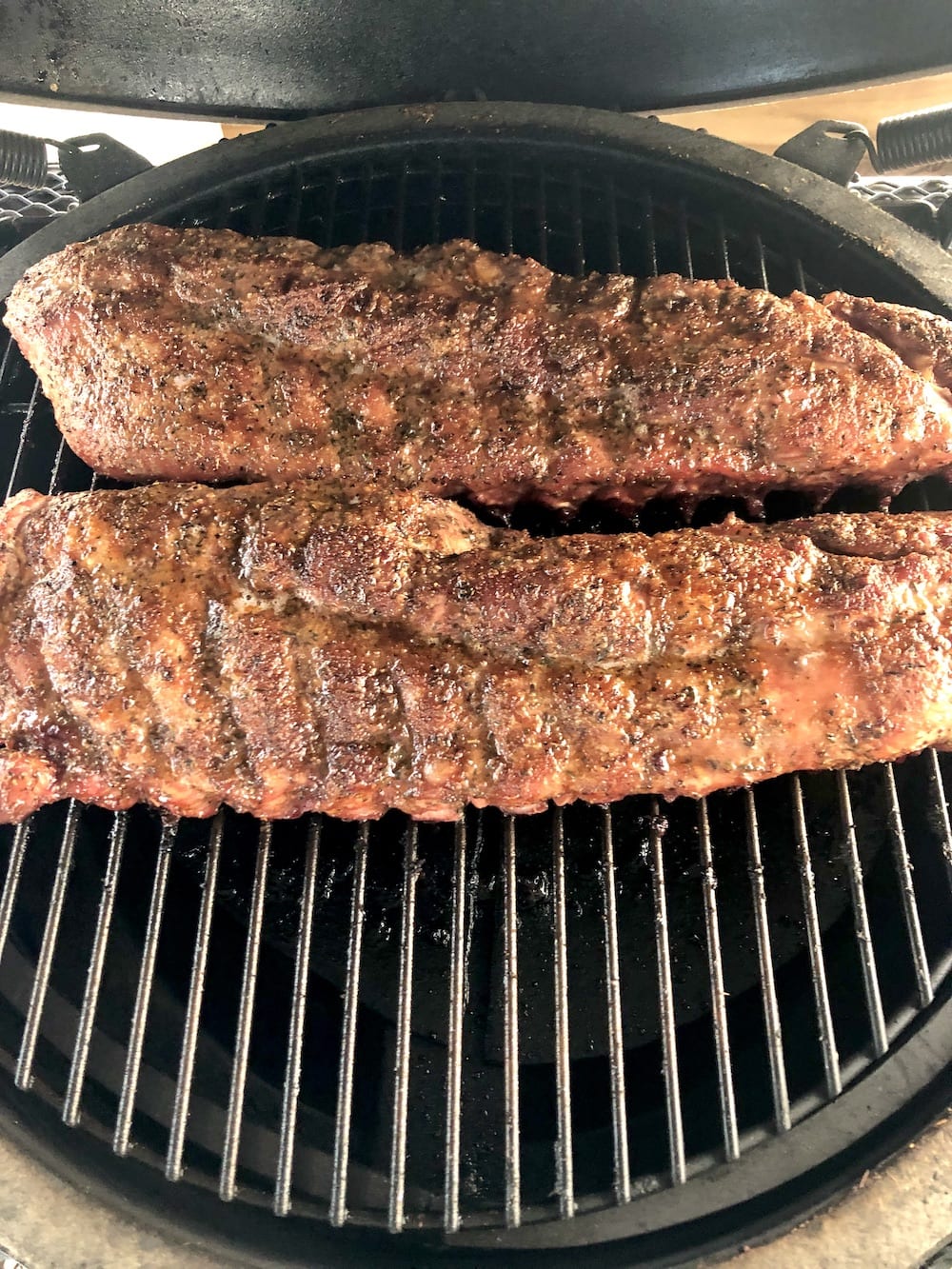 2 racks of dry rubbed ribs on a grill