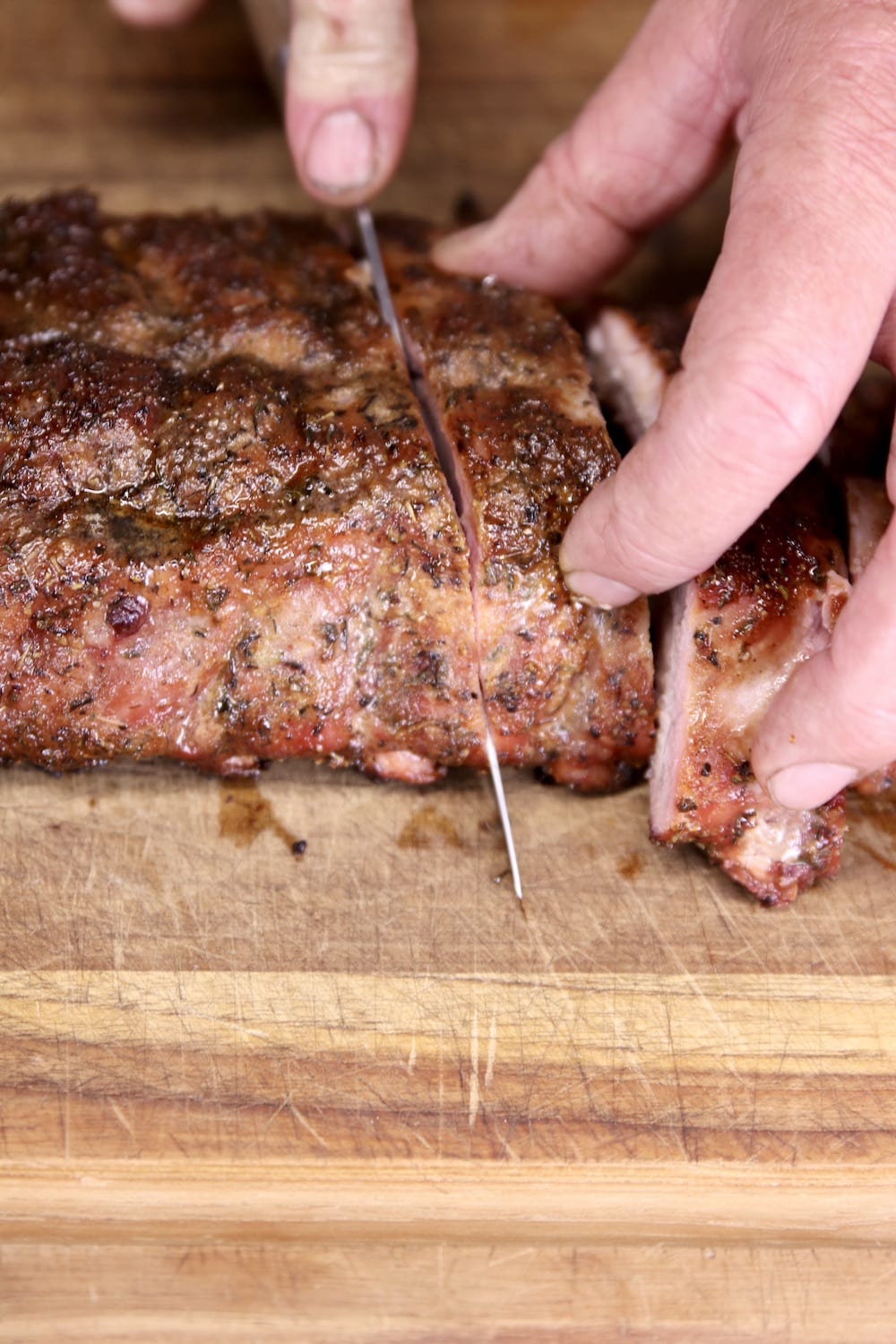 Slicing baby back ribs on a cutting board