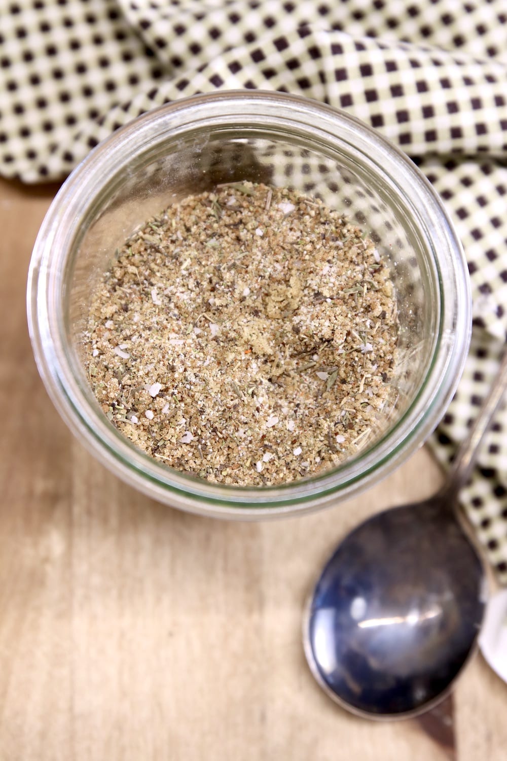 Jar of spice rub with a spoon and check napkin