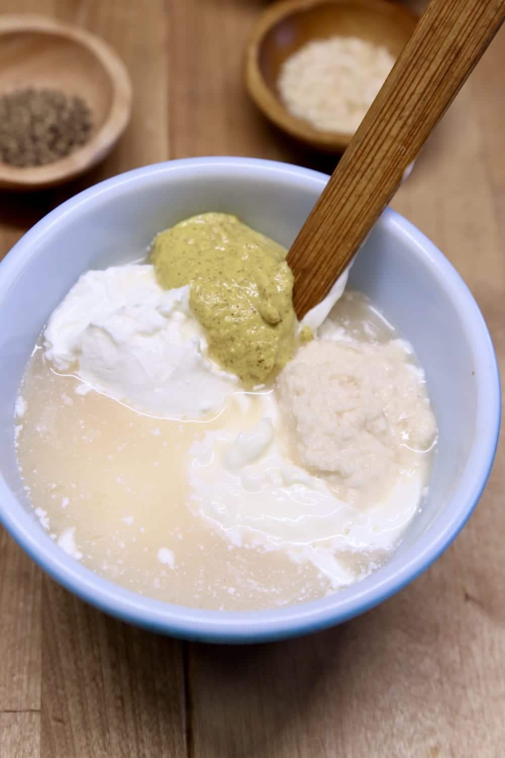 Bowl with mayo, sour cream, mustard, lemon juice with wood handle spoon