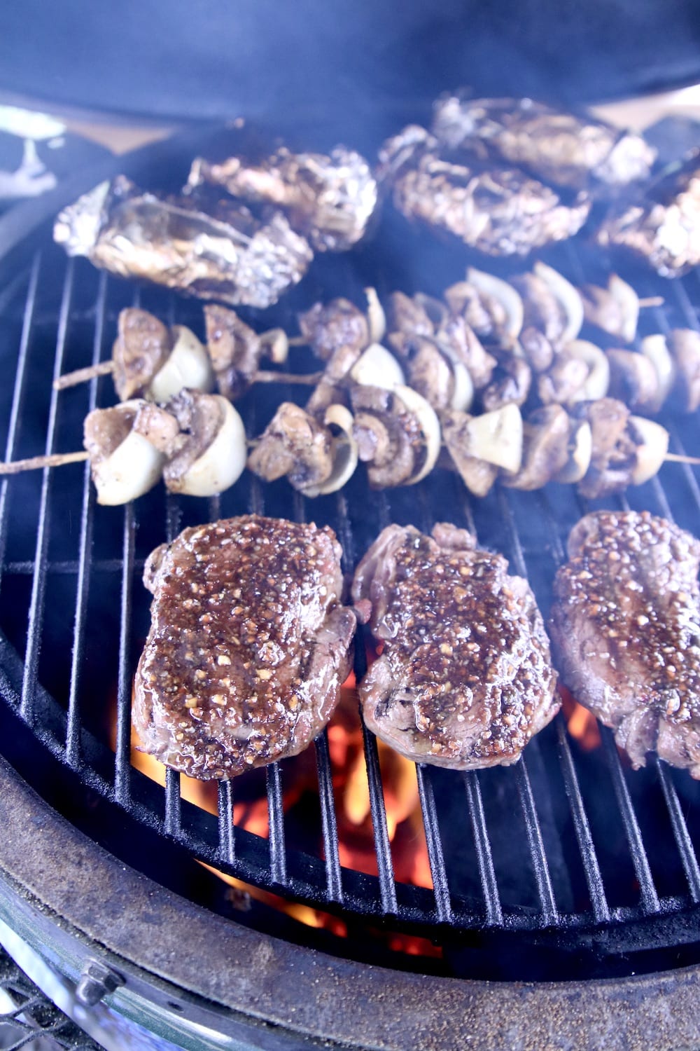 close up of grilling steaks with mushroom skewers