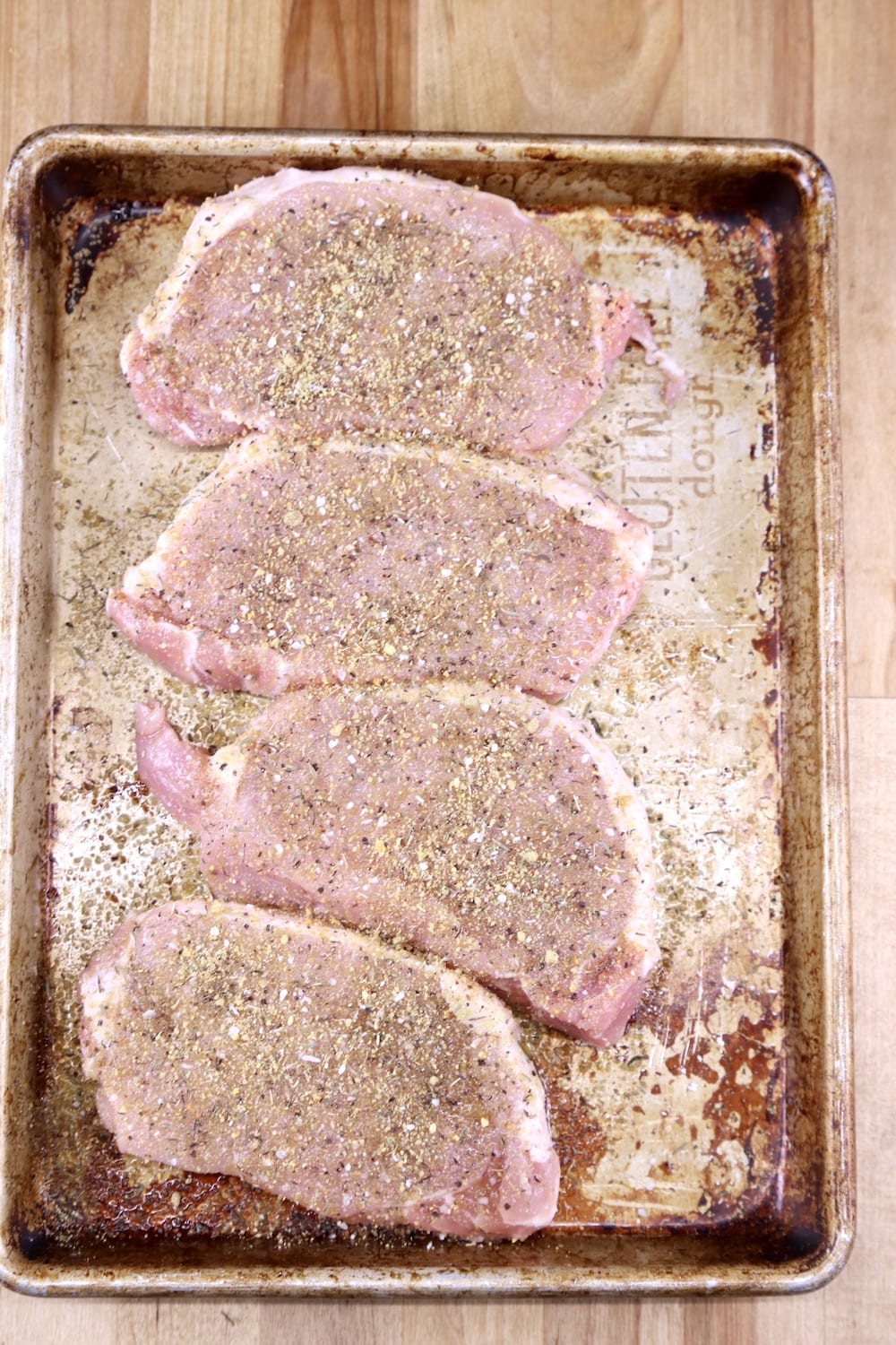 pork chops on a sheet pan with dry rub for grilling