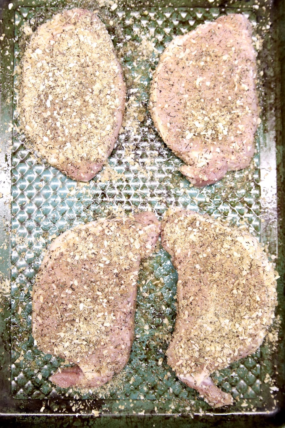 4 pork chops on a baking sheet seasoned with dry rub
