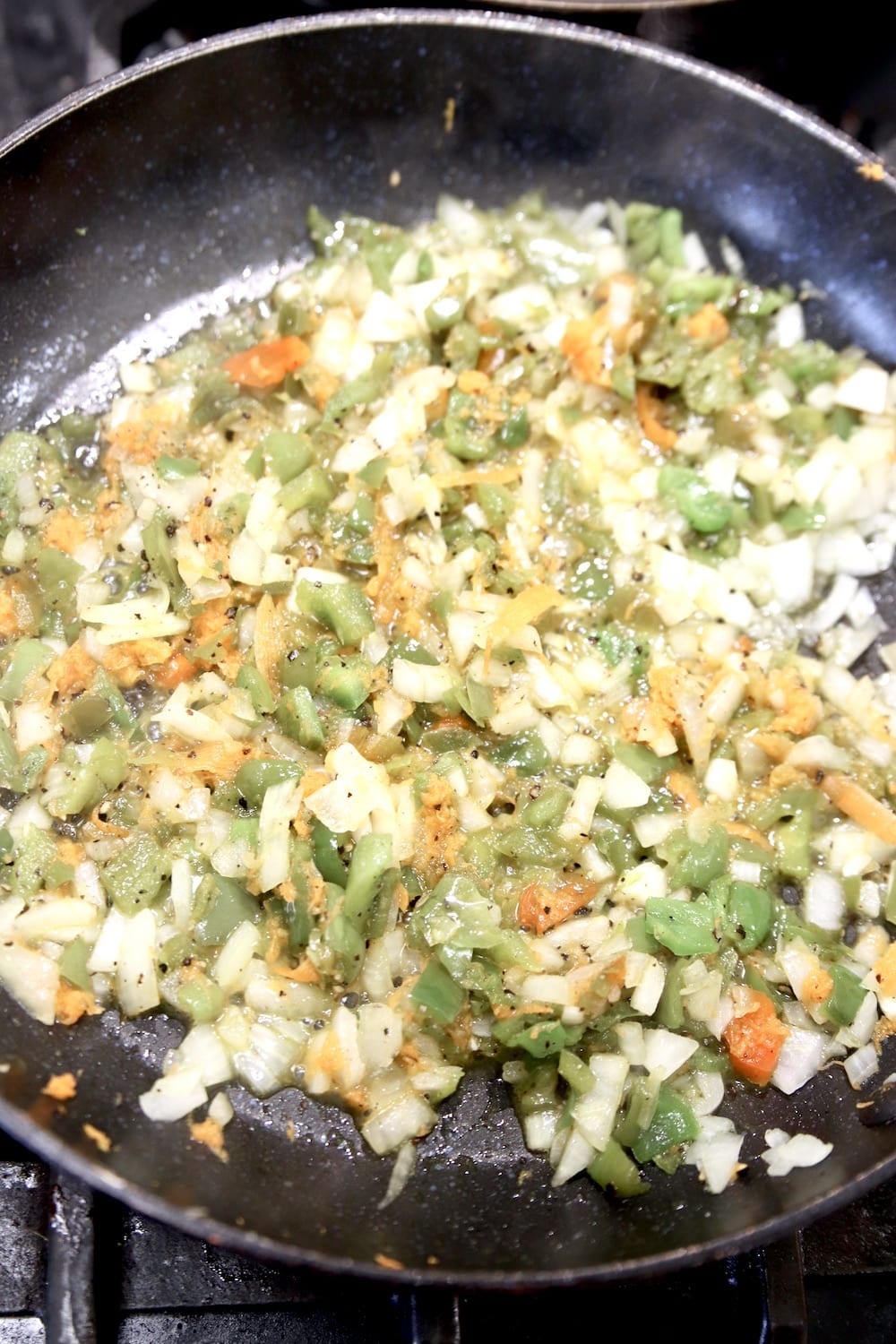 onions, bell peppers, carrots in a skillet