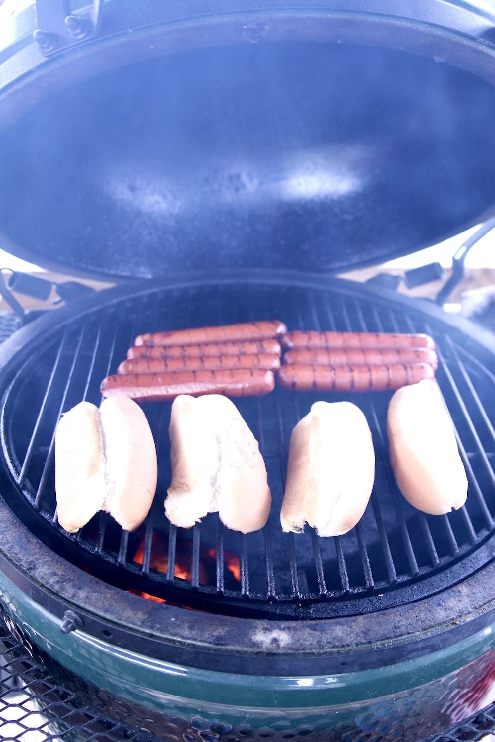 hot dogs on a grill with buns