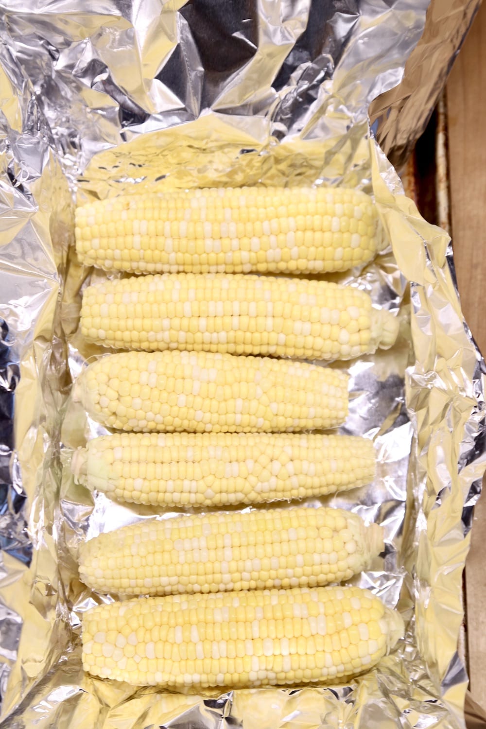 6 ears of husked corn on the cob, on foil lined pan