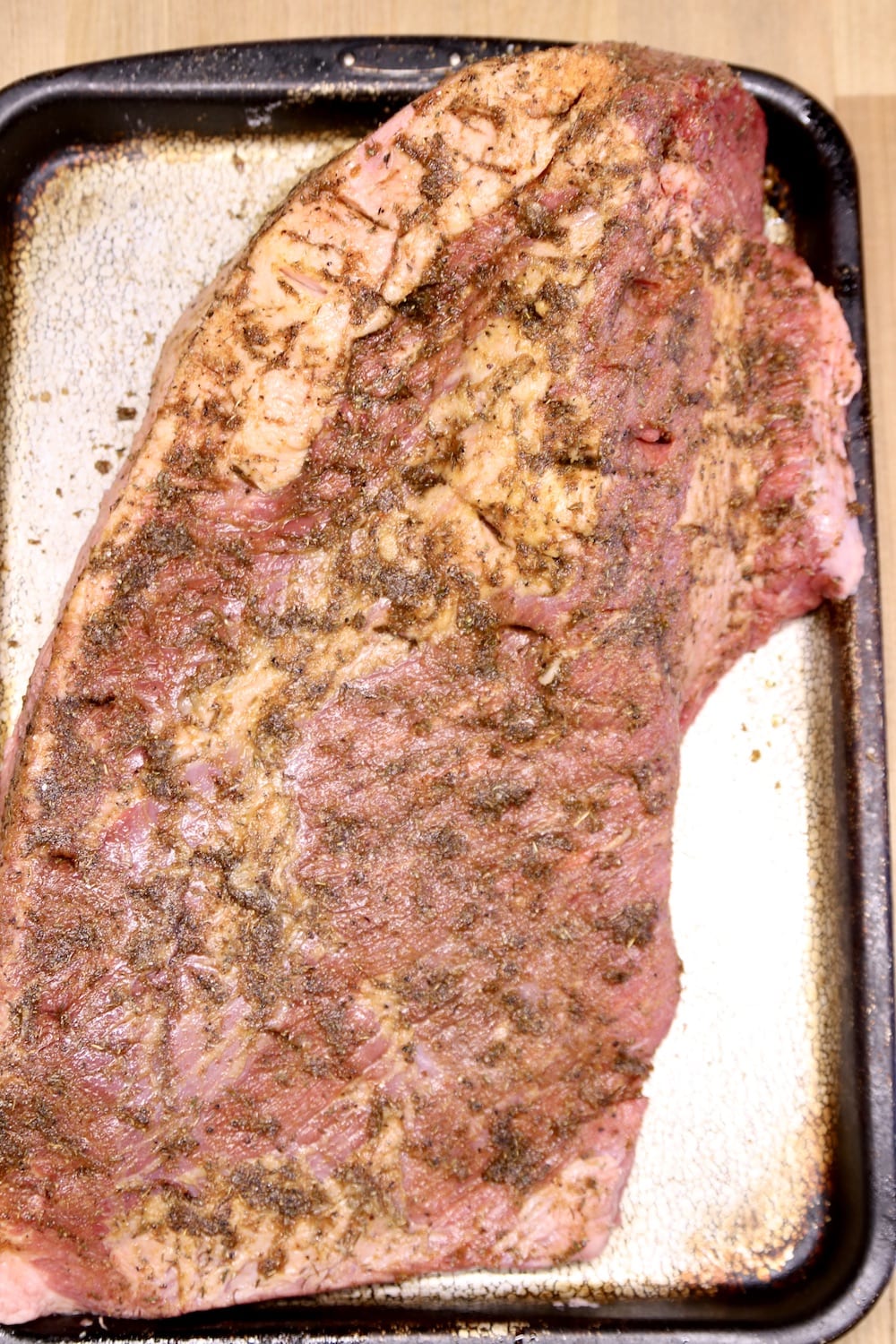 whole brisket rubbed with dry rub on a baking sheet