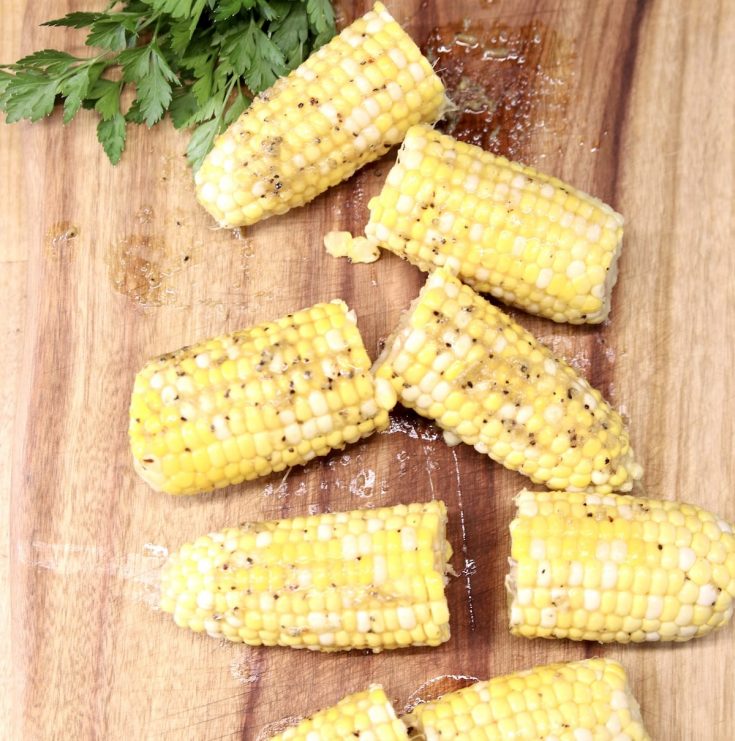 Chile Butter Corn on the Cob on a cutting board - cut in half with fresh parsley