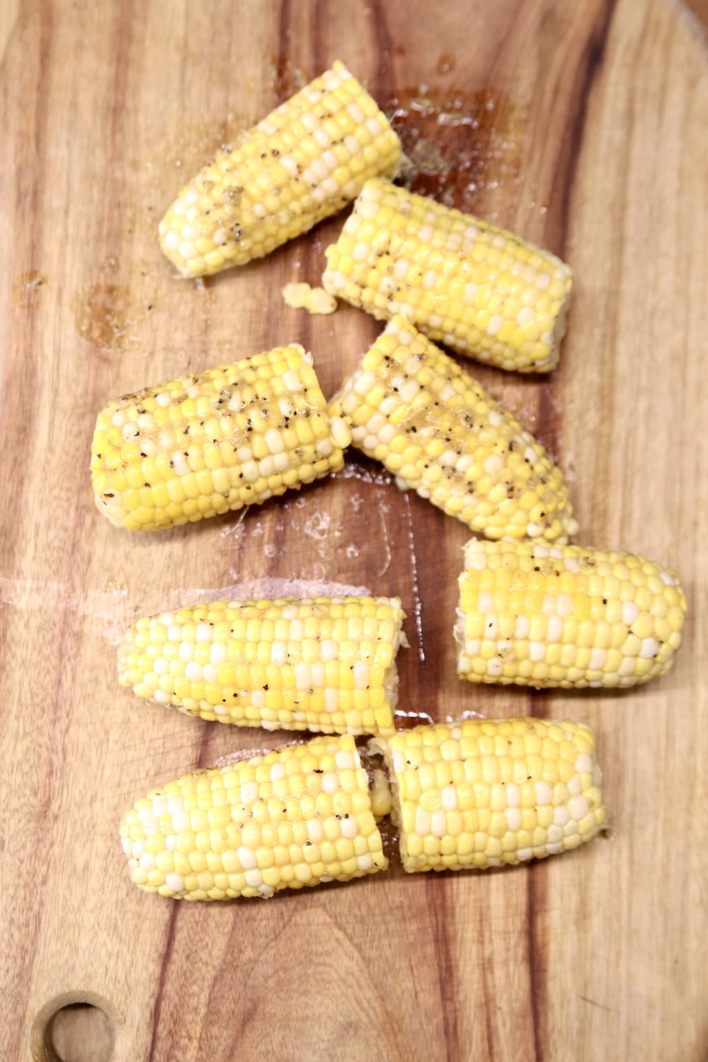 Grilled corn on the cob, on a cutting board - sliced in half