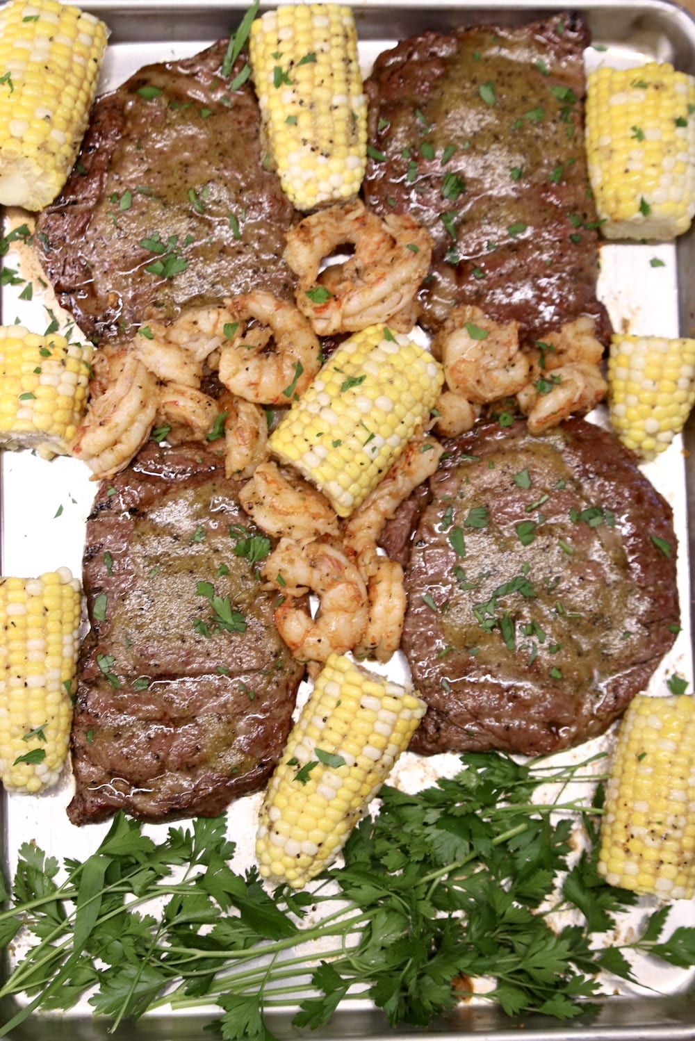 chile butter steaks with shrimp and corn on the cob - on a sheet pan