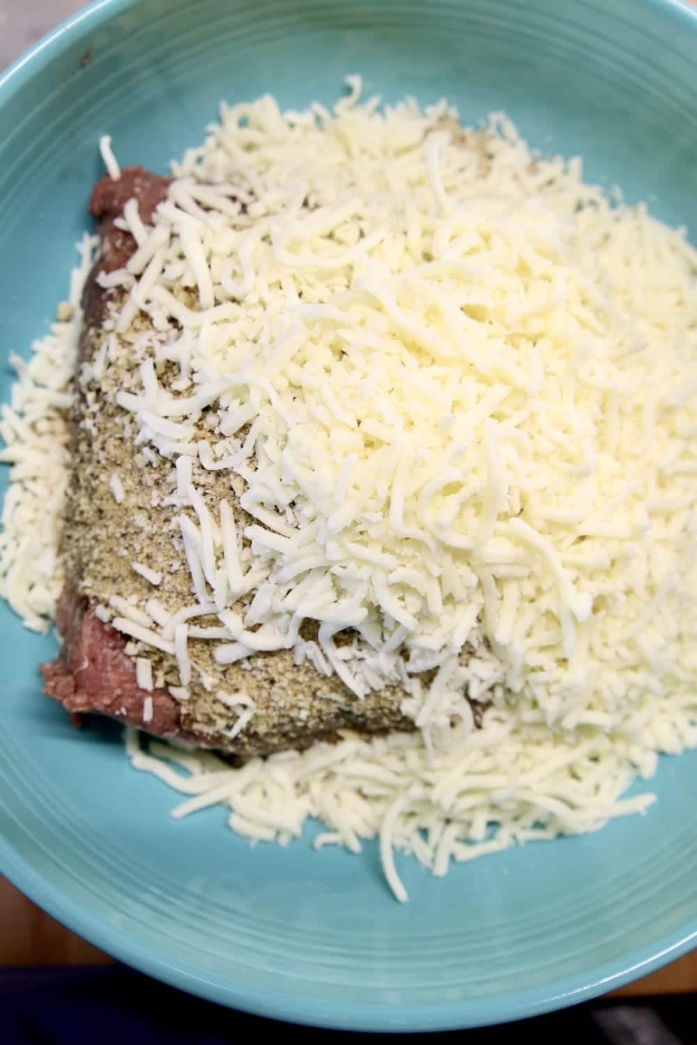ground beef, spices and shredded mozzarella cheese in a bowl