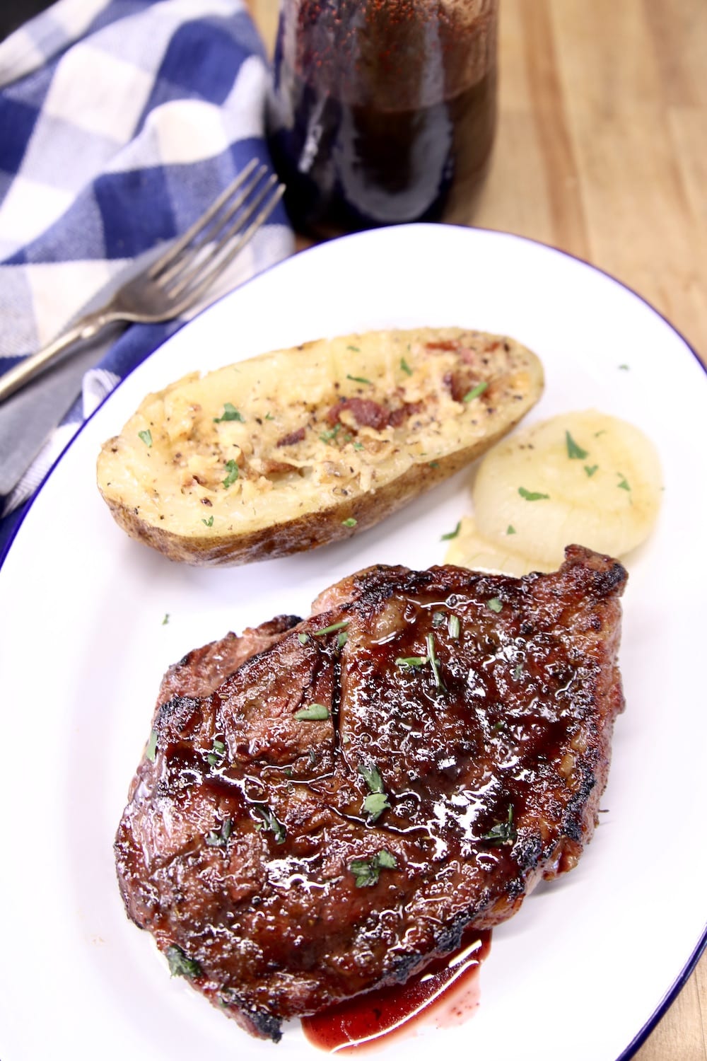 Grilled Ribeye Steak on a plate with baked potato half