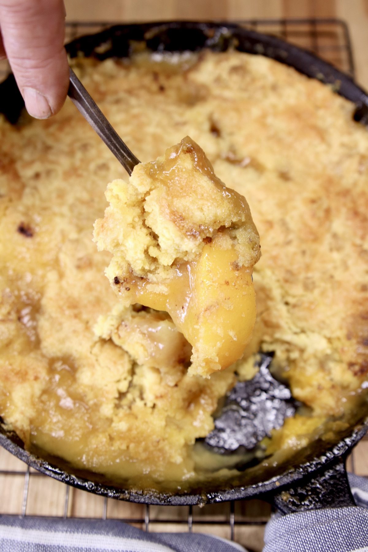 Spoonful of grilled peach cobbler over skillet