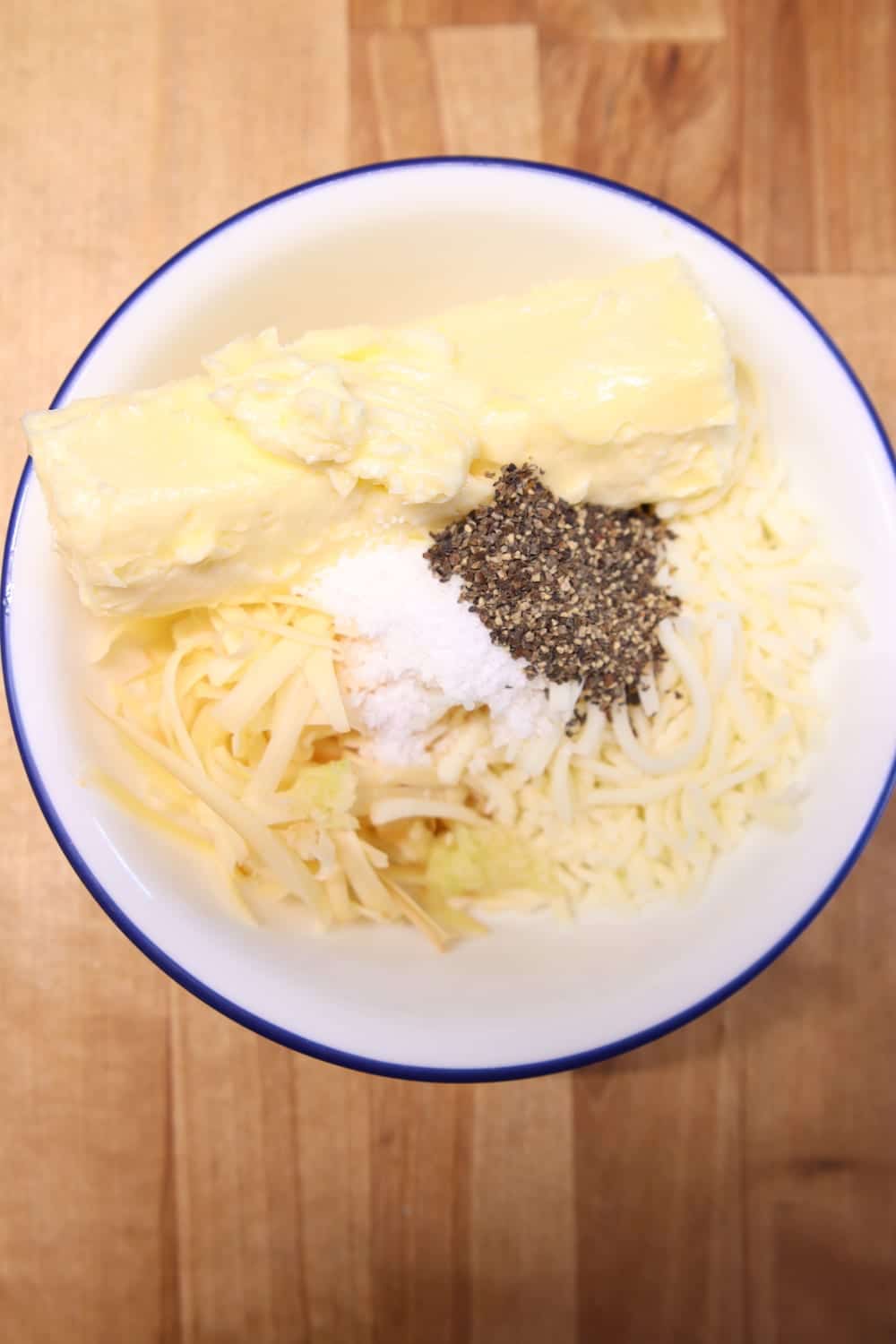 bowl with butter, shredded cheese, garlic, salt and pepper