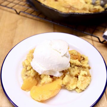 plate with peach cobbler topped with ice cream