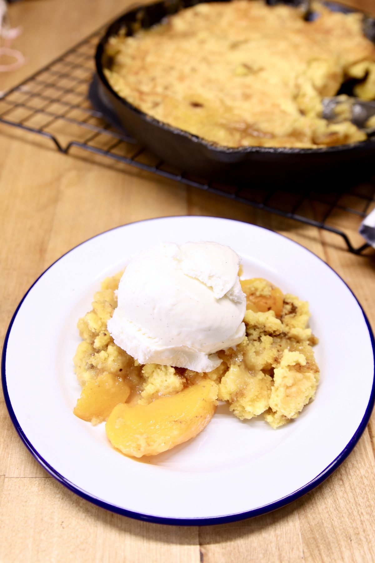peach cobbler on a plate topped with vanilla ice cream
