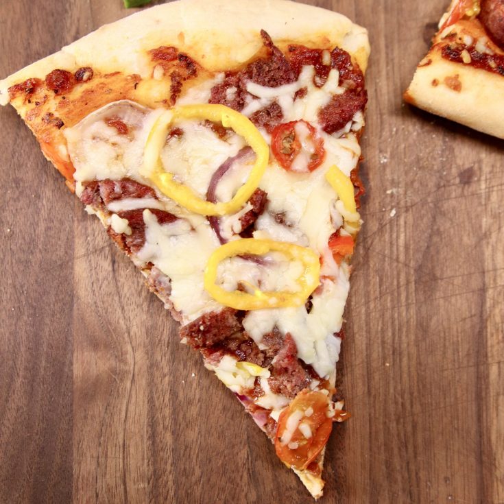 slice of pizza on a walnut cutting board