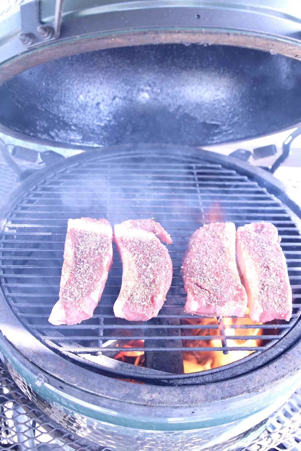 4 NY Strip Steaks on a grill