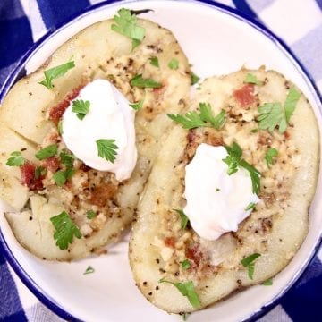 Loaded baked potato on a small bowl with sour cream, bacon and parsley