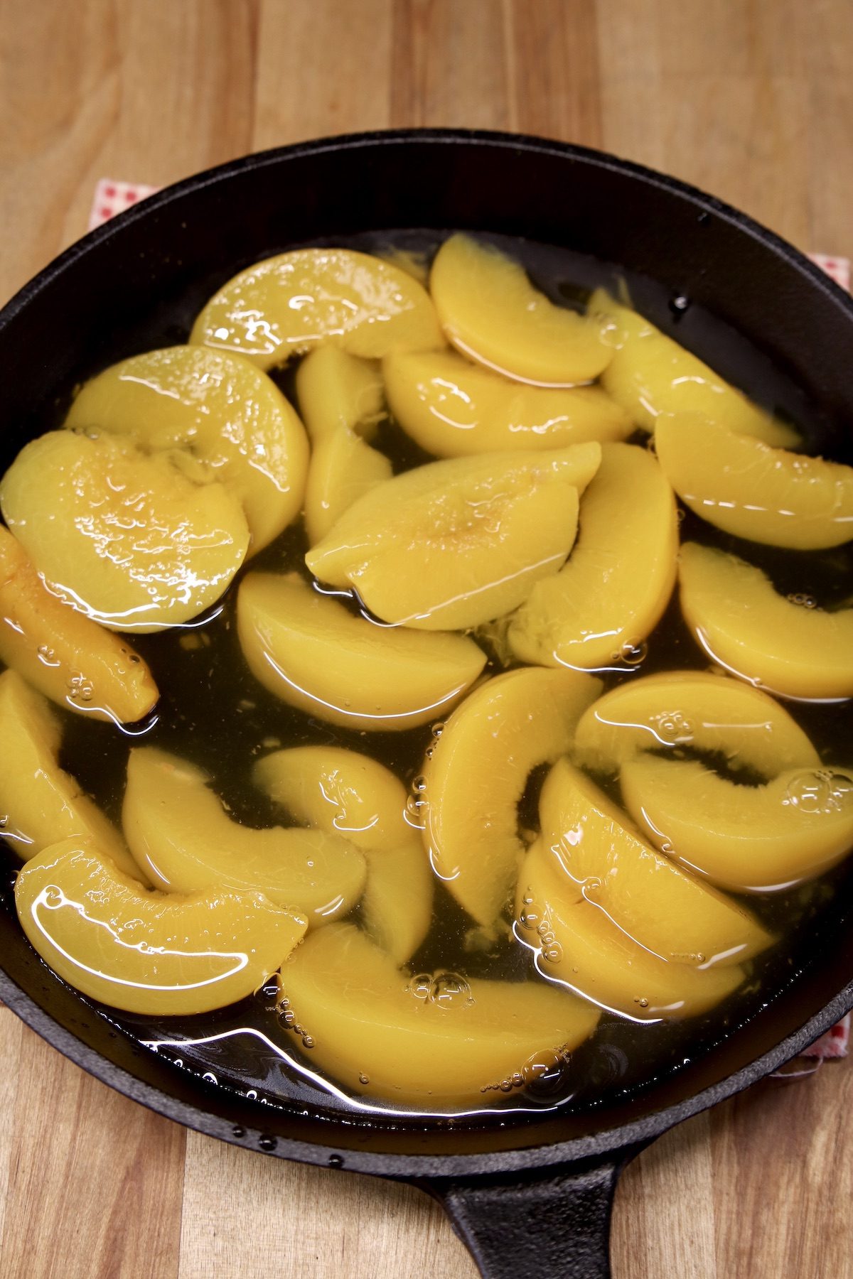 sliced peaches and syrup in a cast iron skillet