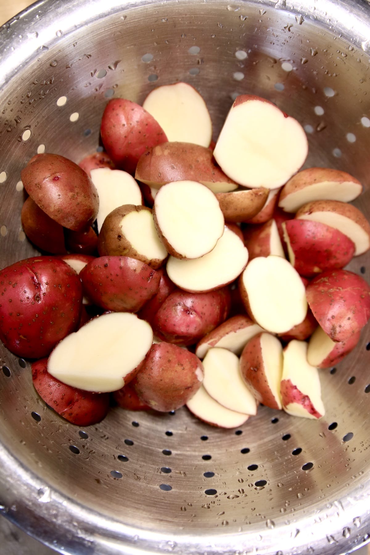 colander of baby red potatoes in a colander, some cut