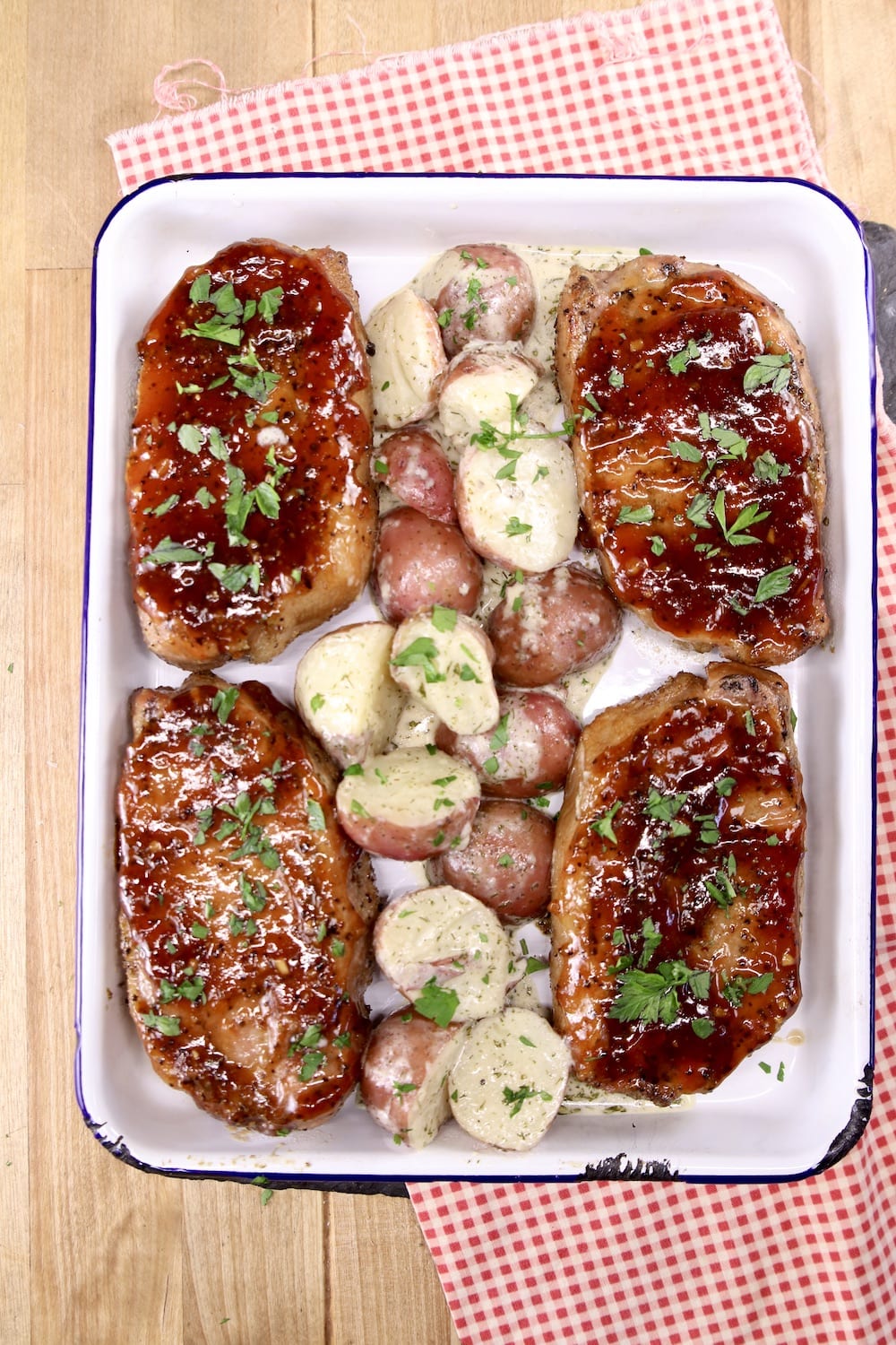 Pan of 4 bbq pork chops with red potatoes in center