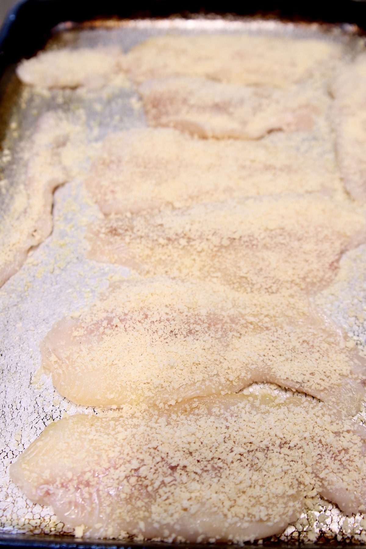 fish filets dredged in panko on a baking sheet
