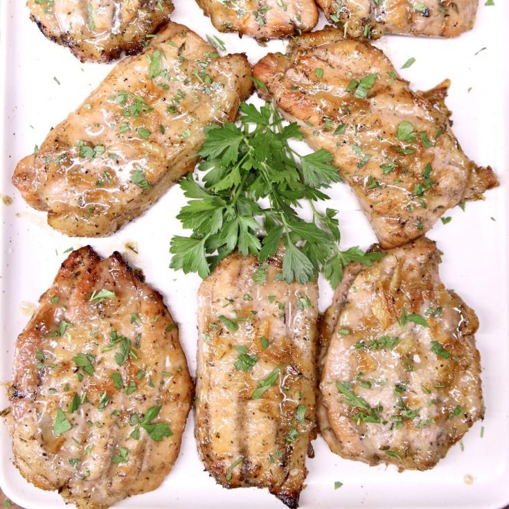 Platter of grilled pork chops with parsley garnish
