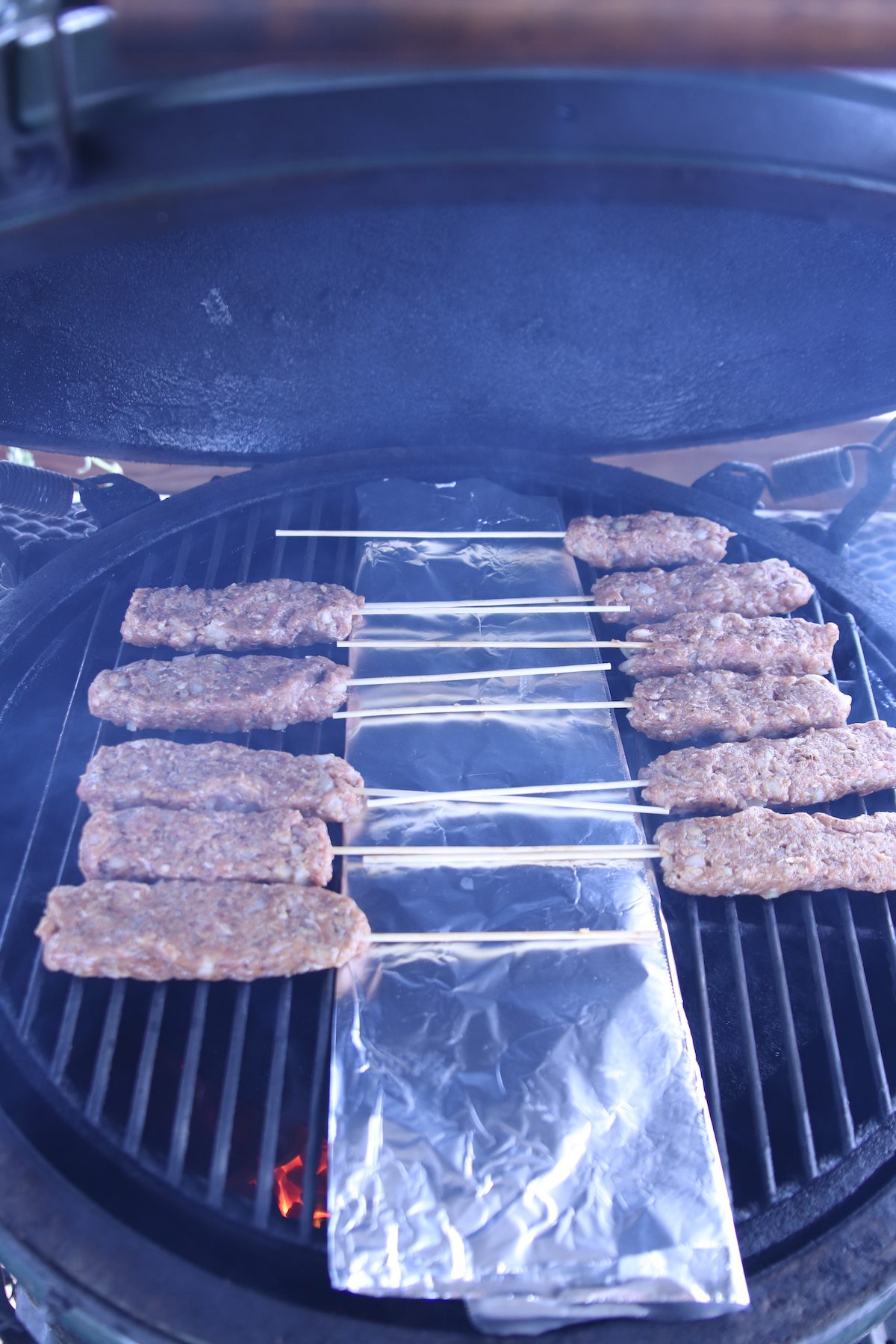 ground beef skewers with foil in center on a grill