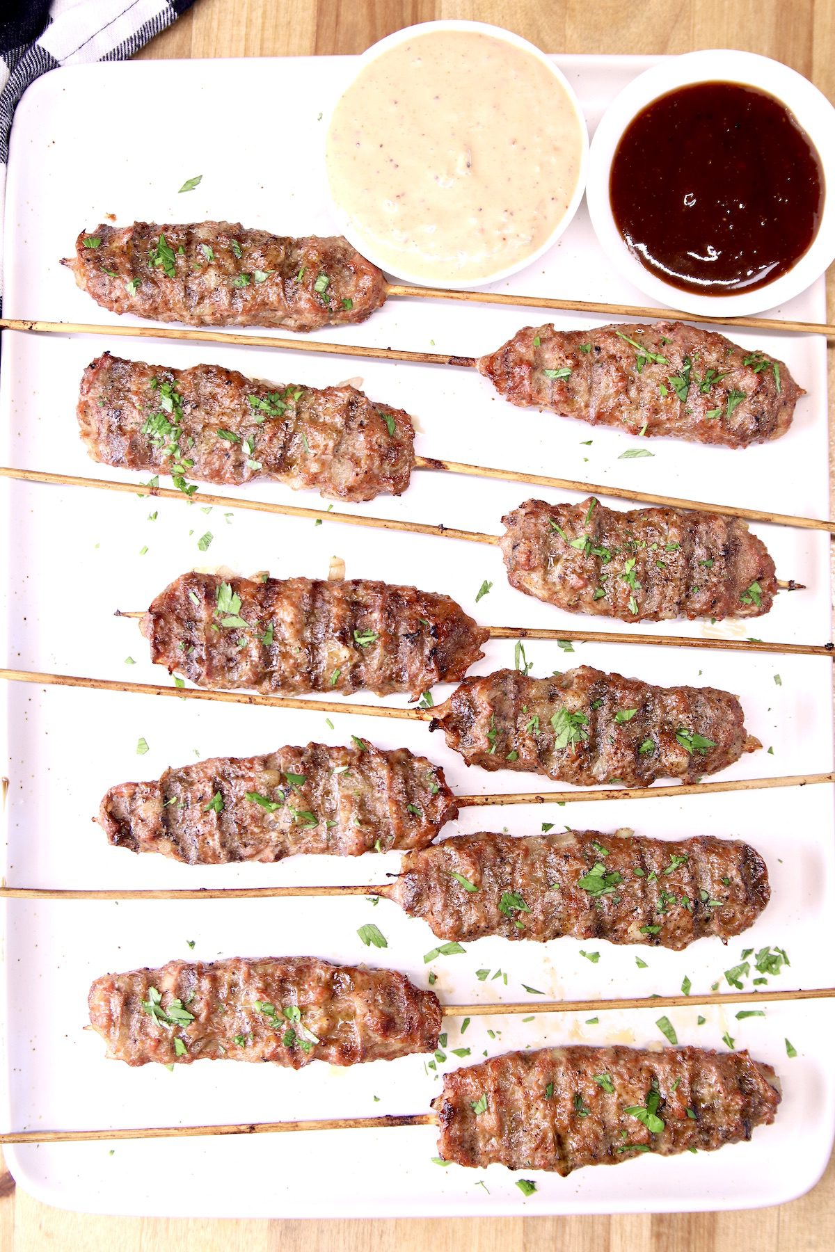 ground beef kabobs on a platter with 2 dipping sauces