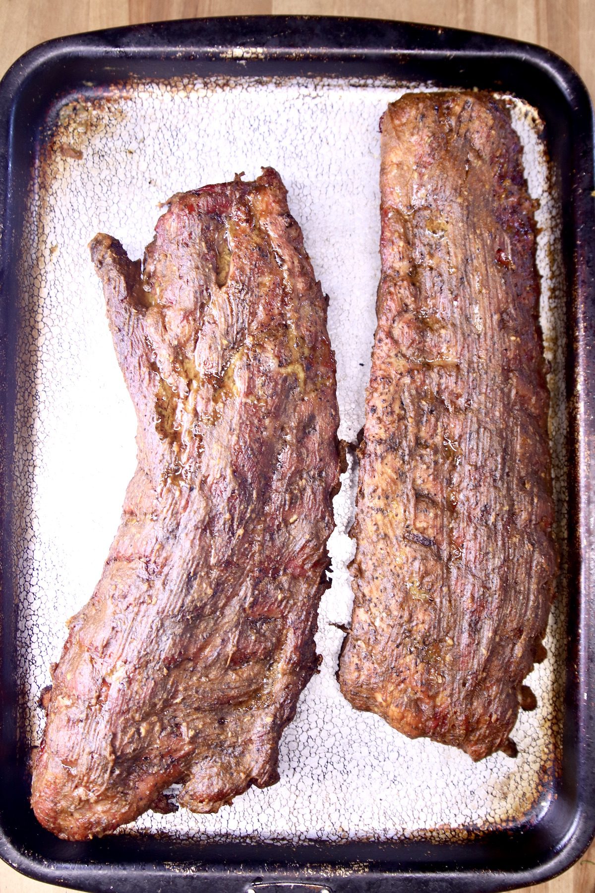grilled baby back ribs resting on a pan