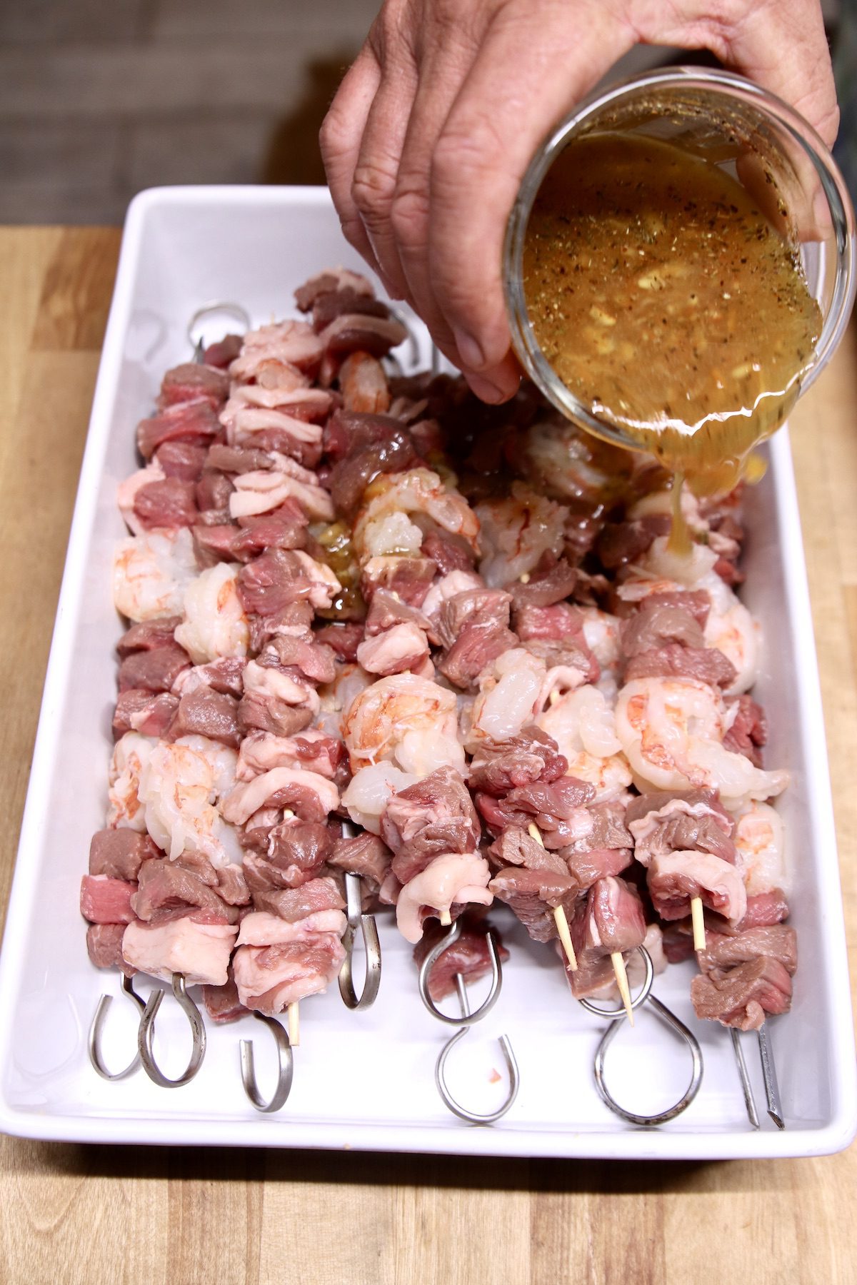 kabobs with steak and shrimp - pouring orange glaze over to marinate