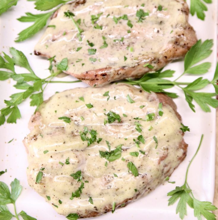 closeup of creamy Italian pork chops with parsley on a platter