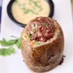 meatloaf stuffed potato on a plate with bowl of honey mustard in background