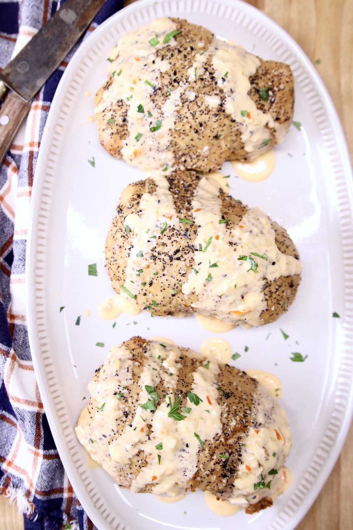 platter of chicken breasts drizzled with cheese sauce