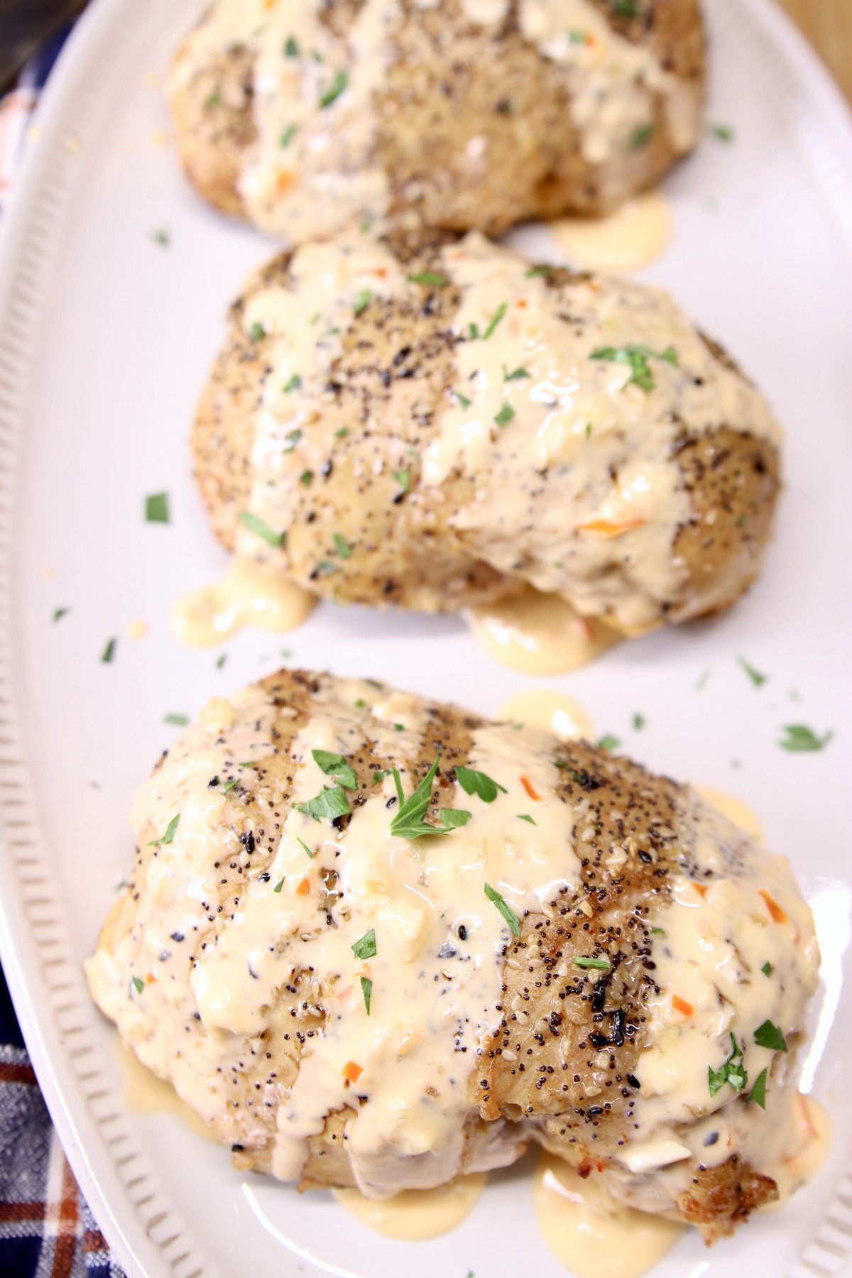 chicken breasts drizzled with cheese sauce on a platter