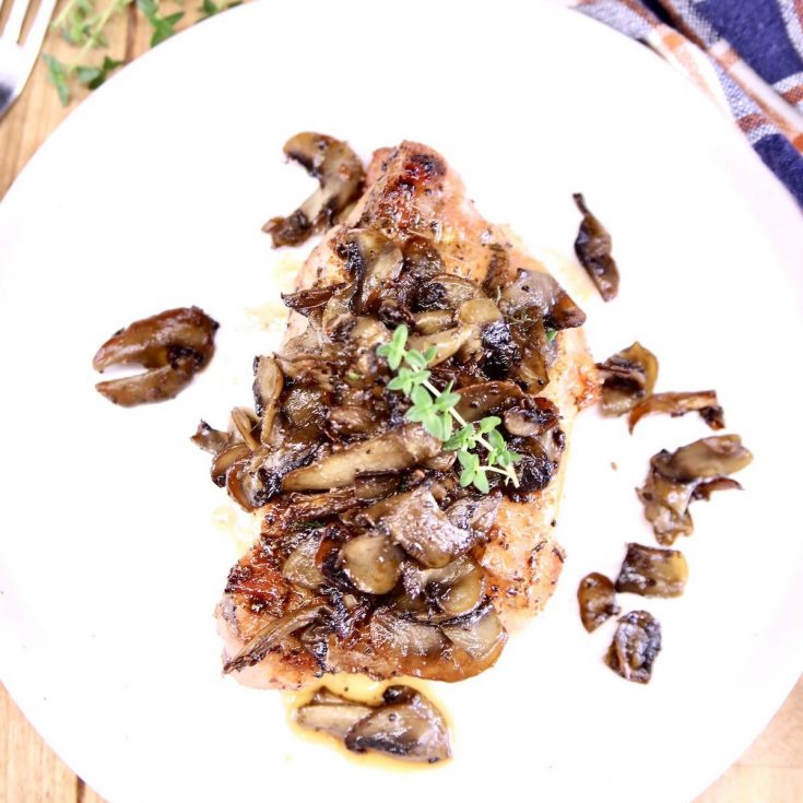 plate with pork chop topped with mushrooms