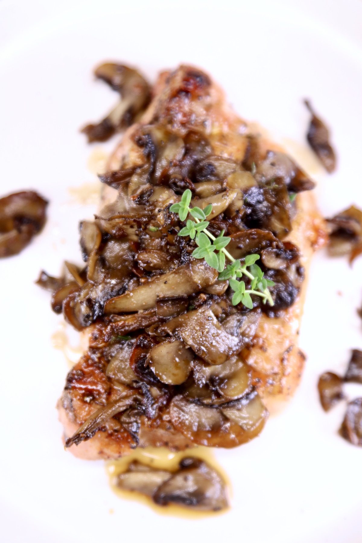 Mushroom pork chop on a plate, fresh thyme garnish